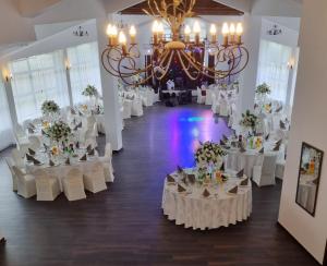 a banquet hall with white tables and chairs and a chandelier at Conca Verde Râșnov in Râşnov