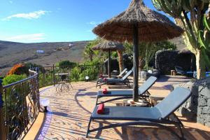 een patio met ligstoelen en een parasol bij JURTE - Traumhafter Meerblick, beheizter Pool, Sauna, Billiard, Tischtennis, Garten in La Asomada