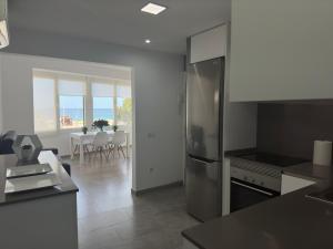 a kitchen with a refrigerator and a table with chairs at Apartamento en primera linea con vistas al mar - VistaMar Blanes in Blanes +6 photos