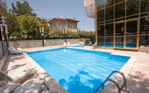 een groot zwembad met stoelen naast een gebouw bij Happy House - Marina Centro in Rimini