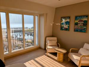 a living room with a couch and a chair and windows at LA VILLA DU PETIT PORT - Appartements & chambres in Aix-les-Bains