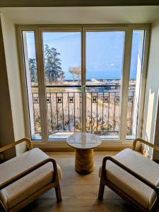 a room with two chairs and a table in front of a window at LA VILLA DU PETIT PORT - Appartements & chambres in Aix-les-Bains