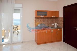 a kitchen with a sink and a microwave and a table at APARTMANI LUX SEA in Utjeha