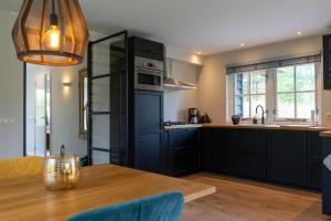 a kitchen with black cabinets and a wooden table at Instuif in Buren