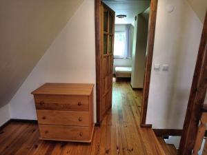 an attic room with a wooden dresser and a door at Domek El Coyote z wędkowaniem in Hoczew