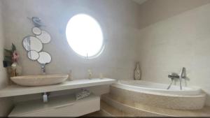 een badkamer met een wastafel, een bad en een spiegel bij Villa al mare in San Felice Circeo