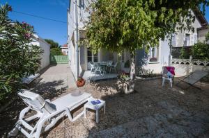 a patio with chairs and a table and a tree at maison proche du marche - 8798 in Soulac-sur-Mer