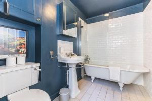 a bathroom with a tub and a sink and a toilet at Leafy & Stylish Brixton Retreat in London