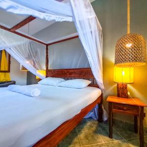 a bedroom with a canopy bed with a table and a lamp at Modern Girasoli Suites 01 in Malindi