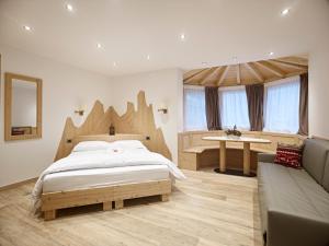 a bedroom with a large bed and a couch at B&B Augusto in Madonna di Campiglio