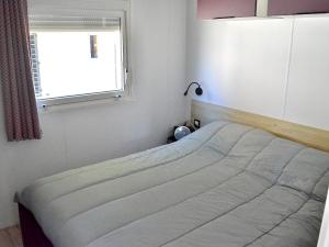a bed in a bedroom with a window at Chalet pour 6 à St-Hilaire - Piscine chauffée in Saint-Hilaire-de-Riez +9 photos