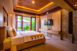 a bedroom with a bed and a television in a room at Jero Kelodan Villa in Tabanan