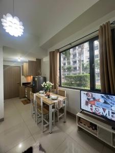 Una sala de estar con un televisor y una mesa con sillas. en Seaside Serenity, en Manila