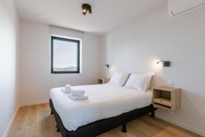 a bedroom with a large white bed with a window at Maison Atlantis in Nieuwpoort