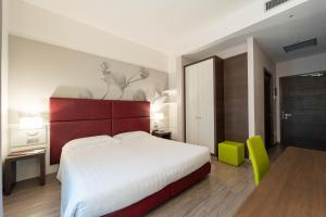 a bedroom with a large white bed and a green chair at Hotel Villa Nabila in Reggiolo