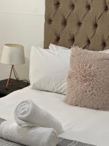 a bed with white sheets and a pillow and a towel at Heart of Numbi Villa in The Sands