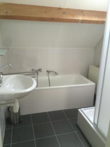 ein Badezimmer mit einer weißen Badewanne und einem Waschbecken in der Unterkunft Oesterbaai 36 in Wemeldinge