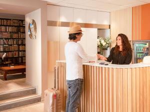 a man and a woman standing at a counter at ibis Styles Beaulieu sur Mer in Beaulieu-sur-Mer