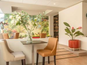 a dining room with a table and chairs and a vase of flowers at ibis Styles Beaulieu sur Mer in Beaulieu-sur-Mer