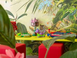 a table with toys on top of it with a painting at ibis Styles Beaulieu sur Mer in Beaulieu-sur-Mer