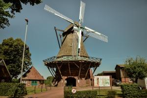 an old windmill in a park with a building at Ferienwohnung Bussjans Hof in Dinklage +4 photos