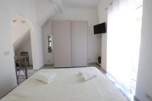 a bedroom with a large white bed with two towels on it at La Dolce Vita in Taormina
