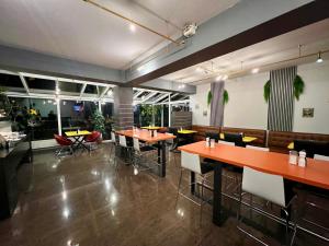 a restaurant with orange tables and chairs and windows at Globotel Hotel Garbsen in Garbsen