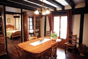 a dining room with a wooden table and a bedroom at Casa Rural Mokorrea in Etxalar