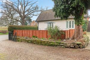 a fence in front of a house with a tree at The Lodge Cottage in Oxton