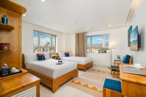 岘港Ocean Bliss Hotel - Free Sauna的有两张床和一张书桌的酒店房间 更多37张照片