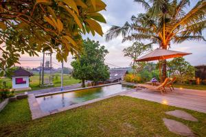 an umbrella and a bench next to a pool at Jero Kelodan Villa in Tabanan