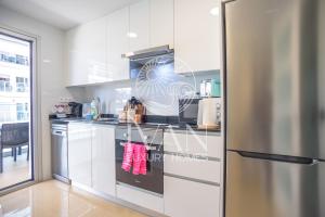 a kitchen with white cabinets and a stainless steel refrigerator at Casa Mariposa Ivan Luxury Homes 3ªPlta Norte 1ªLínea in Oropesa del Mar