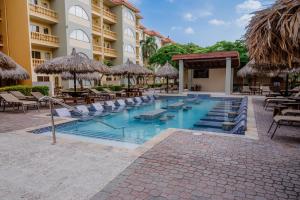 a swimming pool at a resort with chairs and umbrellas at Eagle Aruba Resort in Palm-Eagle Beach
