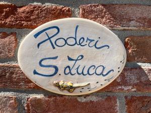 Un cartello su un muro di mattoni con un calabrone sopra. di Poderi S Luca ad Alba