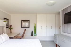 Un dormitorio blanco con una cama y un escritorio. en Mossel Bay Golf Retreat 1BR Luxury Escape, en Mossel Bay