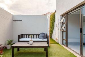 Un pequeño patio con un banco y una mesa. en Mossel Bay Golf Retreat 1BR Luxury Escape, en Mossel Bay