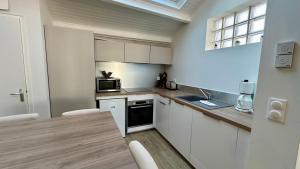 a kitchen with white cabinets and a wooden table at Maison 4 personnes, en centre ville in Le Crotoy