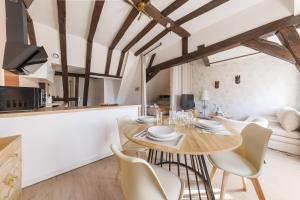 eine Küche und ein Esszimmer mit einem Holztisch und Stühlen in der Unterkunft L’Alcôve Bourbonnaise - Au coeur de Montluçon in Montluçon + 5 Fotos