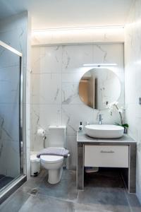 Un baño con lavabo, inodoro y espejo. en Anora Apartment, en Preveza