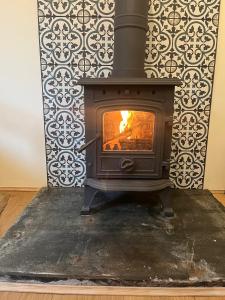 a wood stove in a room with a wall at 1 Rock Cottages in Treknow