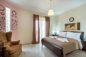 a bedroom with a bed with a chair and a clock at Sunlit sea view apartments in Stalos +30 photos