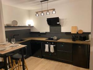 a kitchen with black cabinets and a table with chairs at Appartement - Cambrai in Cambrai +4 photos