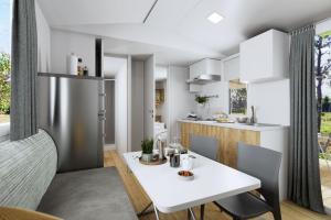 a kitchen and dining room with a white table and chairs at Camping Village Lido di Classe in Lido di Classe