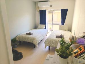 a small room with two beds and a window at 豆インプラス in Saitama