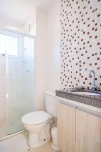 a bathroom with a toilet and a sink and a shower at Apartamento encantador San Roman in Bauru