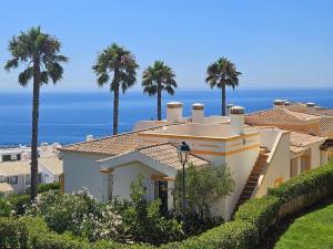 a house with palm trees and the ocean in the background at The View – Santo António Villas, Golf & Spa in Salema