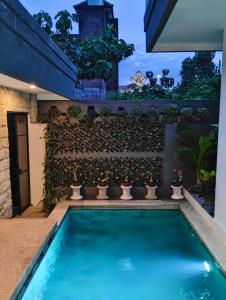 une piscine en face d'un mur orné de plantes dans l'établissement Villa Bella Jimbaran, à Jimbaran