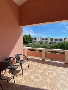 a patio with two chairs and a table and a balcony at Apartman Tamaris in Vir