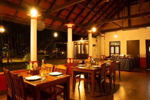 a restaurant with wooden tables and chairs with lights at Palmgrove Lake Resort in Alleppey