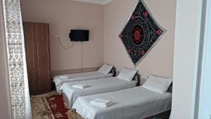 Una habitación con tres camas y un televisor en la pared. en Sogda, en Samarkand